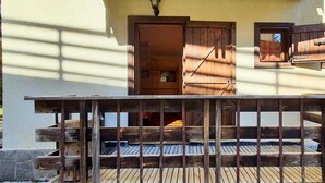 A wooden deck with a railing, a door, and a window with shutters. - Maison des skieur- ski out (Sestriere)