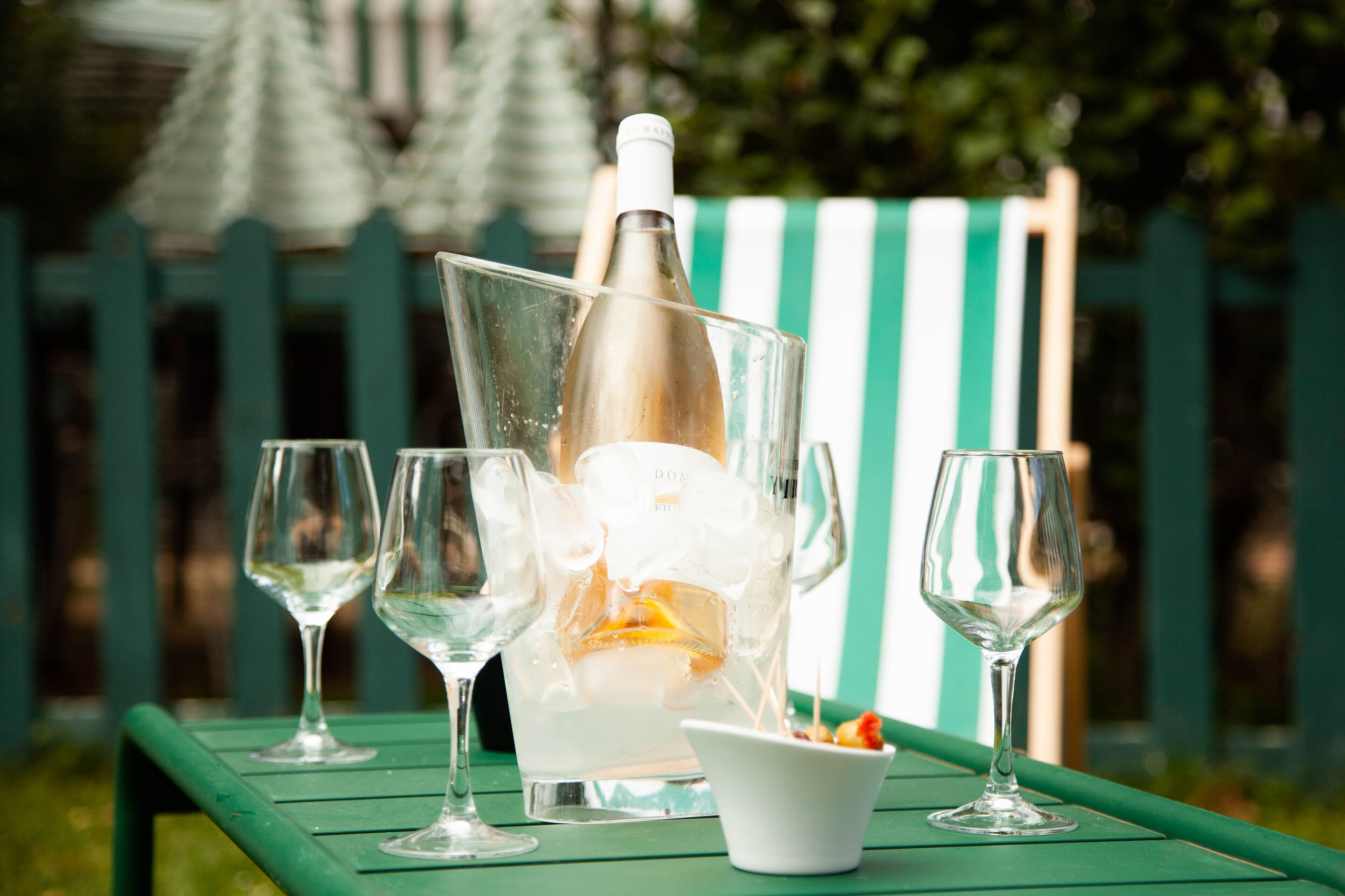 Een tafel met een champagnefles, ijsblokjes en twee lege wijnglazen.