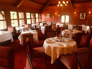A restaurant with multiple round tables set for dining, featuring white tablecloths and red upholstered chairs. - Le Fruit Défendu (Rueil-Malmaison)