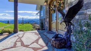 A stone building with a wooden door, a bird sculpture, and a view of mountains.