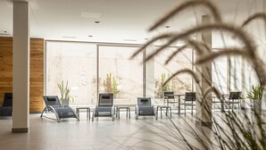 Un'area d'attesa moderna con poltrone relax, ampie finestre e piante da interno.