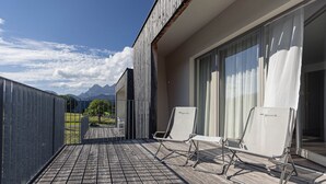 Un balcone con due poltrone, un pavimento in legno e vista sulle montagne.