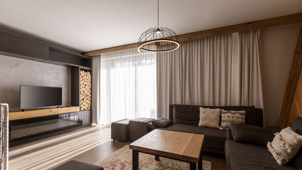 Una sala de estar moderna con un televisor de pantalla plana, una mesa de centro de madera, un sofá y un amplio ventanal con cortinas.