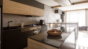 Una cocina moderna con armarios oscuros, una isla de madera y un amplio ventanal que proporciona luz natural.