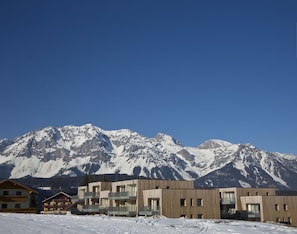 A modern building with multiple balconies and a mountain backdrop.