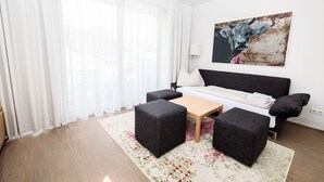 Una sala de estar moderna con un sofá, dos otomanas, una mesa de centro y un cuadro en la pared.