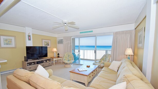 A living room with a television, beige sofas, a coffee table, and a view of the ocean. - Beachmark 3D-Oceanfront 73rd St, Free WiFi, Pool, Elev, W/D, AC (Ocean City)