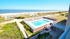 A swimming pool with sun loungers, surrounded by a wooden deck and a white fence, overlooking a beach. - Beachmark 3D-Oceanfront 73rd St, Free WiFi, Pool, Elev, W/D, AC (Ocean City)