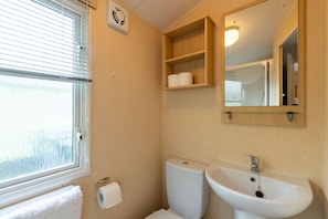 A bathroom with a toilet, sink, and window.