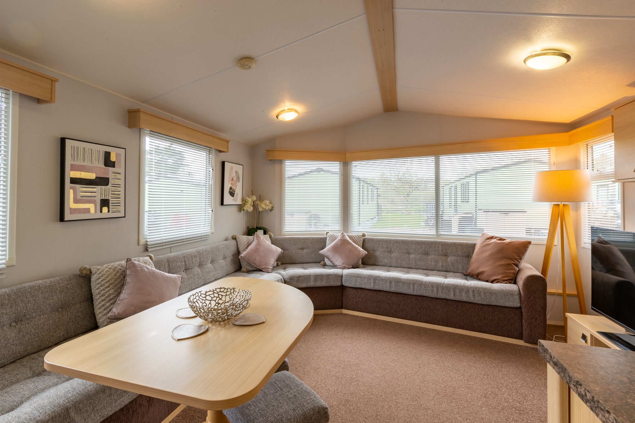 Ein gemütliches Wohnzimmer mit einer Eckcouch, einem Holztisch und einer Stehlampe.