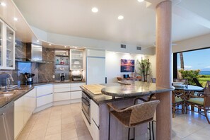 A modern kitchen with a curved island, built-in appliances, and a view of the outdoors.