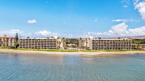 A beachfront hotel with multiple buildings, a beach, and clear skies.