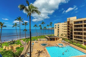 Un hotel con piscina, palmeras y vista al océano.