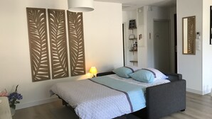 A bedroom with a bed, a bedside lamp, decorative wall panels, a wardrobe, and a mirror. - LE Logis DES Jalles (Saint-Médard-en-Jalles)