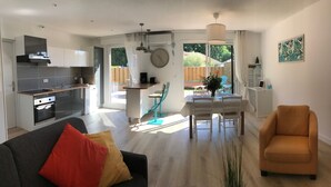 A modern kitchen with a dining area, a sofa, and a TV. - LE Logis DES Jalles (Saint-Médard-en-Jalles)