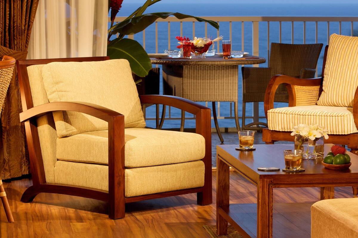 A wooden-framed chair and sofa set with a view of the ocean.