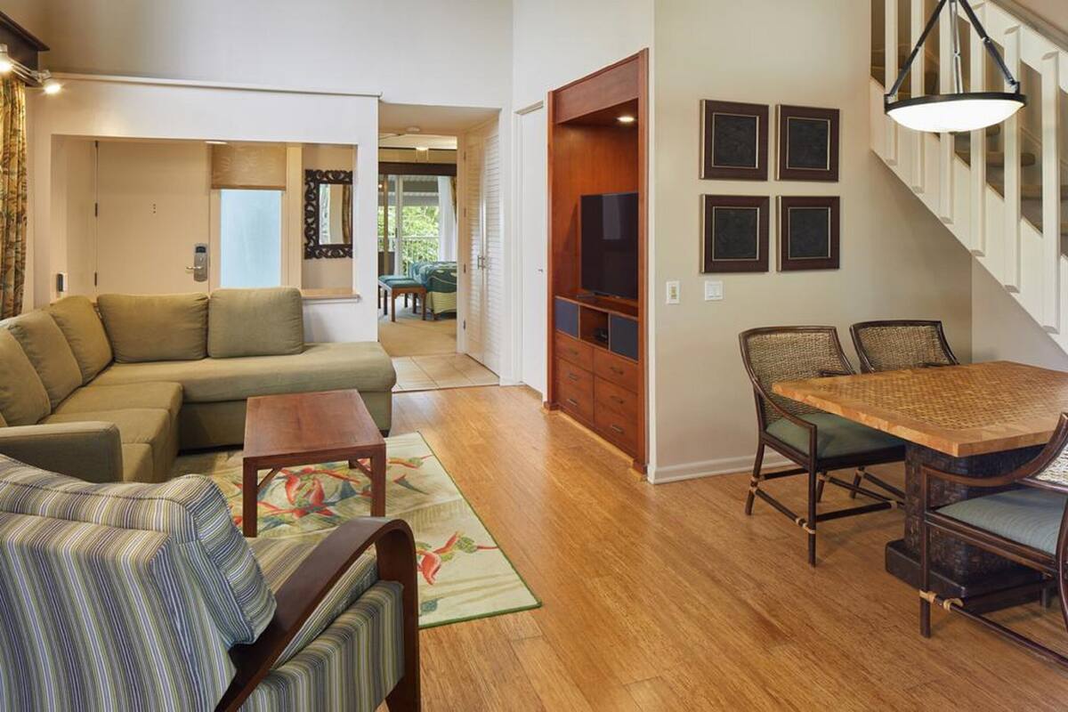 A living room with a sofa, a coffee table, and a dining area with a table and chairs.