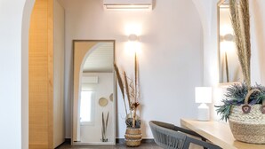 Un interior moderno con una escalera de madera, una cesta tejida sobre una mesa y un espejo en la pared.