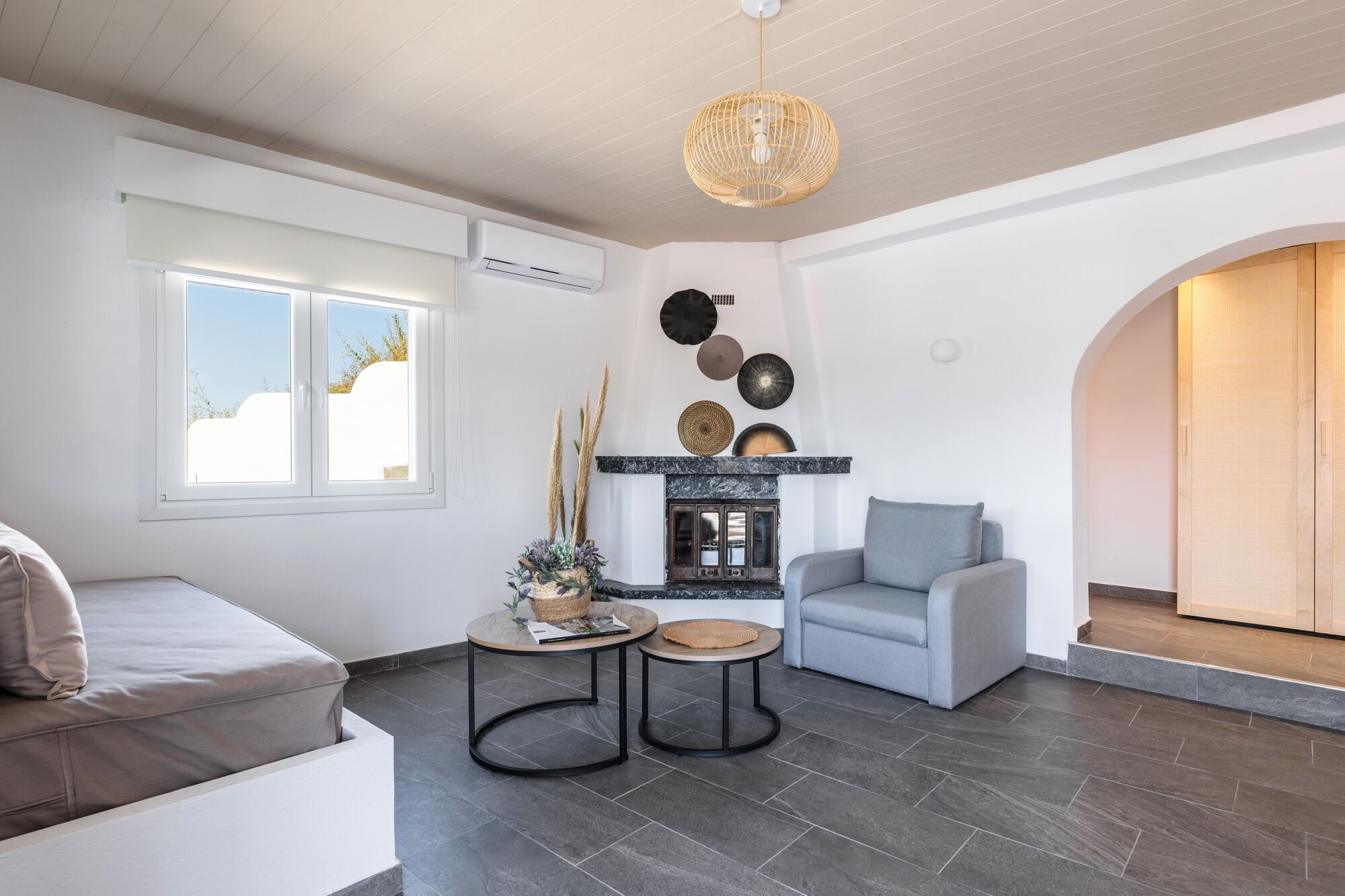 Una sala de estar moderna con chimenea, un sofá, una mesa de centro y una lámpara colgante.