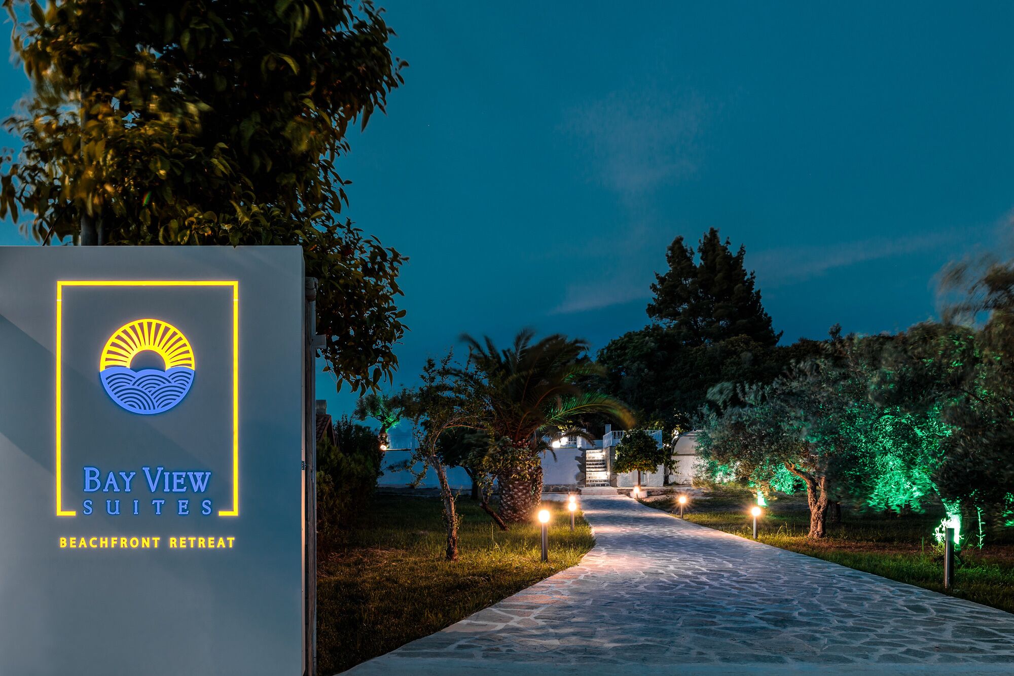 A pathway leading to a building with a sign for Bay View Suites, indicating a beachfront retreat.