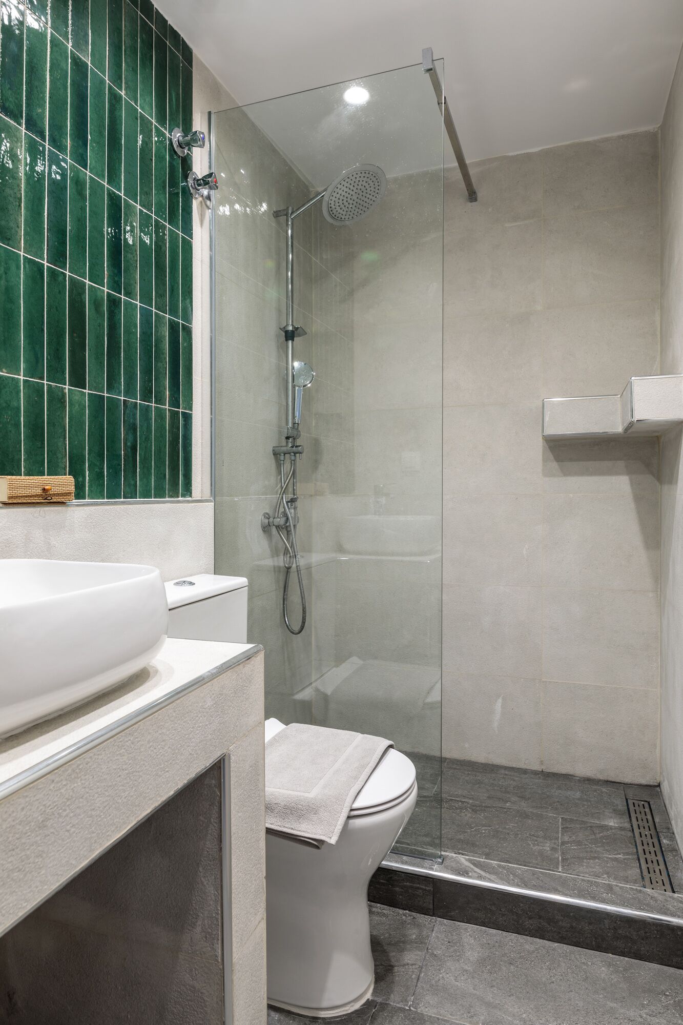 Ein modernes Badezimmer mit einer Duschkabine, einem weißen Waschbecken und einer Toilette.