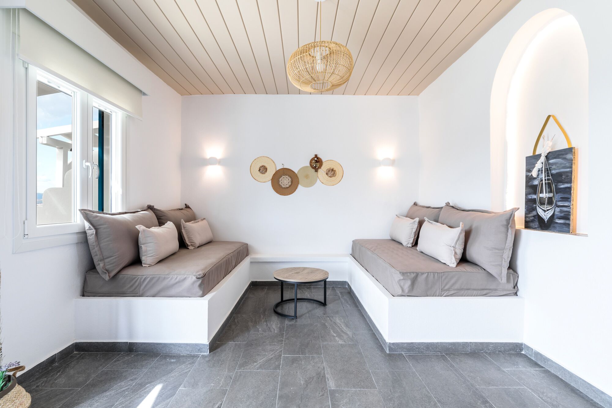 A modern interior with two seating areas, a round table, and a wall-mounted light fixture.