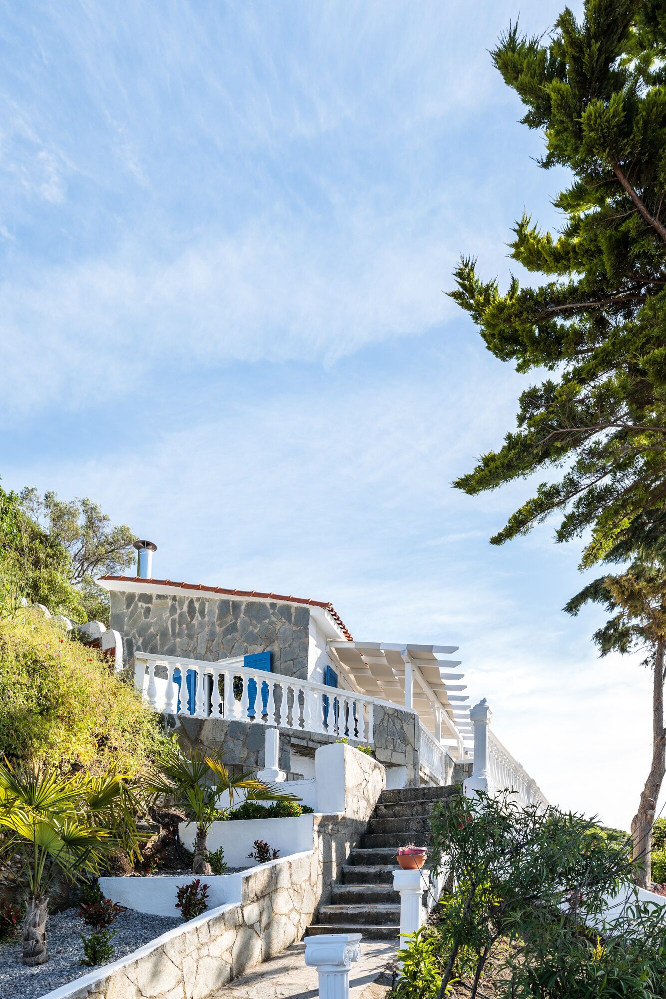 A stone building with a stone staircase leading to a white balcony with blue accents.
