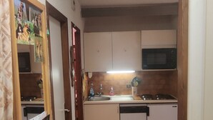 Cozinha compacta com micro-ondas, pia e uma pequena lixeira.