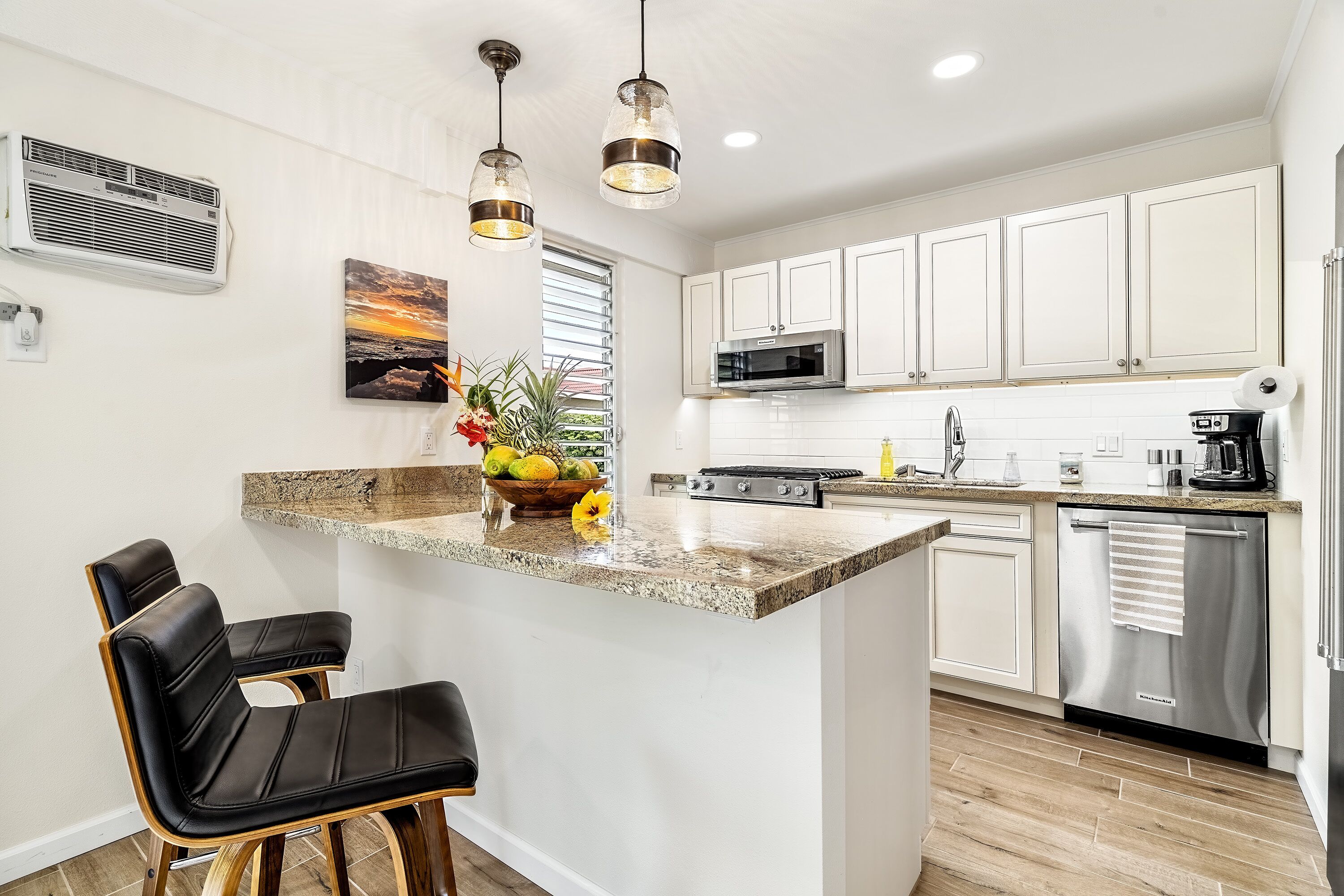 A modern kitchen with white cabinets, a granite countertop, a built-in microwave, and a stainless steel dishwasher.