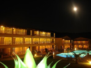 A multi-story hotel with balconies and a swimming pool at night. - Corfu Village Studios (Corfu)
