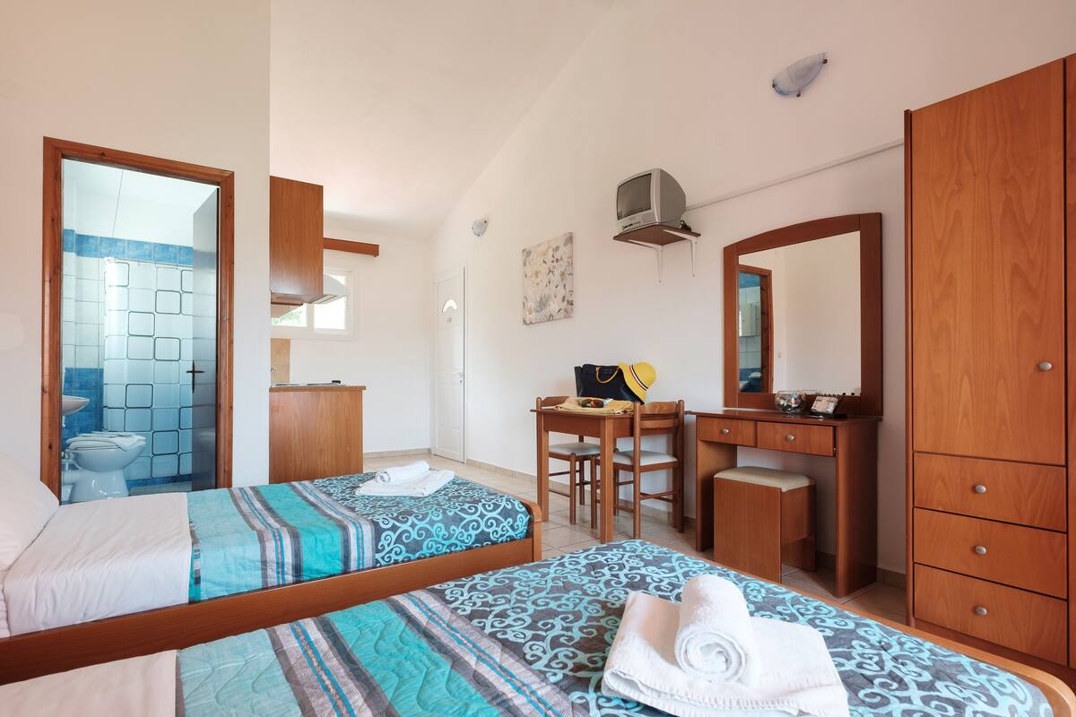 Un dormitorio con dos camas, un escritorio, una silla, un tocador y un armario.