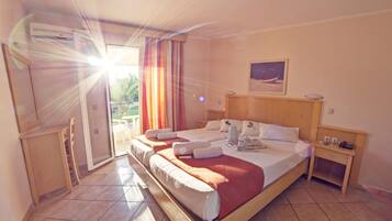 Una habitación de hotel con cama, mesita de noche, escritorio y ventana con cortinas.