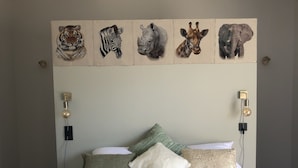 Ein Schlafzimmer mit einem Bett, Kissen und einem Wandbild mit Tierköpfen.