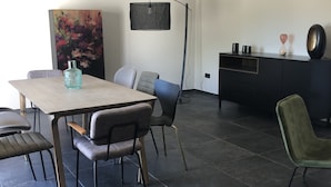Ein zeitgemäßer Essbereich mit Holztisch, gepolsterten Stühlen, einer Stehlampe und einem Bild an der Wand.