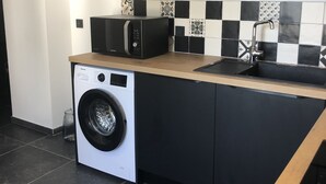 Eine kleine Küche mit Waschmaschine, Mikrowelle und Spüle.