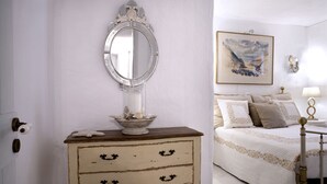A bedroom with a bed, a bedside table with a mirror, a dresser with drawers, and a painting on the wall. - EXECUTIVE VILLA WITH PRIVATE SWIMMING POOL (PAROS)