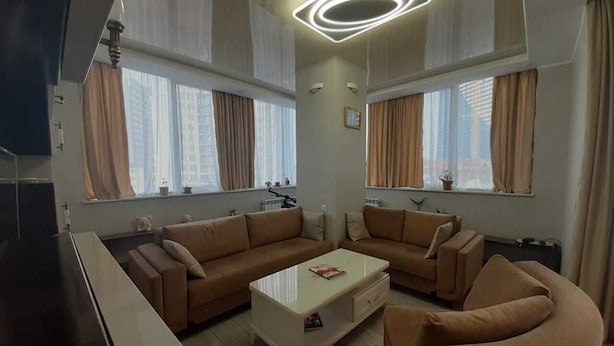 A modern living room with a sectional sofa, a coffee table, and a flat-screen TV. - Уютная квартира в Батуми с джакузи. (Batumi)