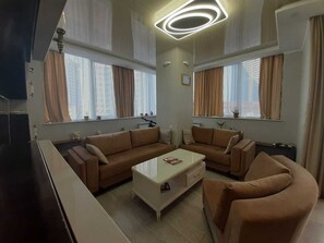Un salon moderne avec un canapé d’angle, une table basse et un téléviseur à écran plat.