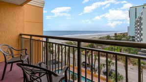 A balcony with a view of the beach and ocean.