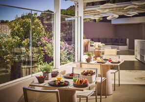Un desayuno con una mesa, sillas y vistas a un jardín a través de amplios ventanales.