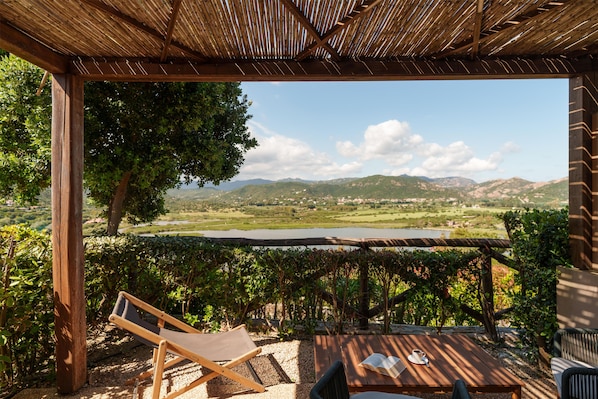 Una pérgola de madera con vista a un lago y montañas.