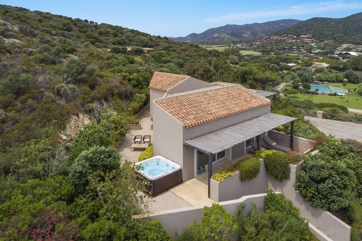 Ein modernes Haus mit Whirlpool, umgeben von üppiger Vegetation und Hügeln.