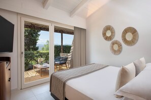 Un dormitorio con cama, televisor y puerta corrediza de vidrio que da a un balcón con mesa y sillas.