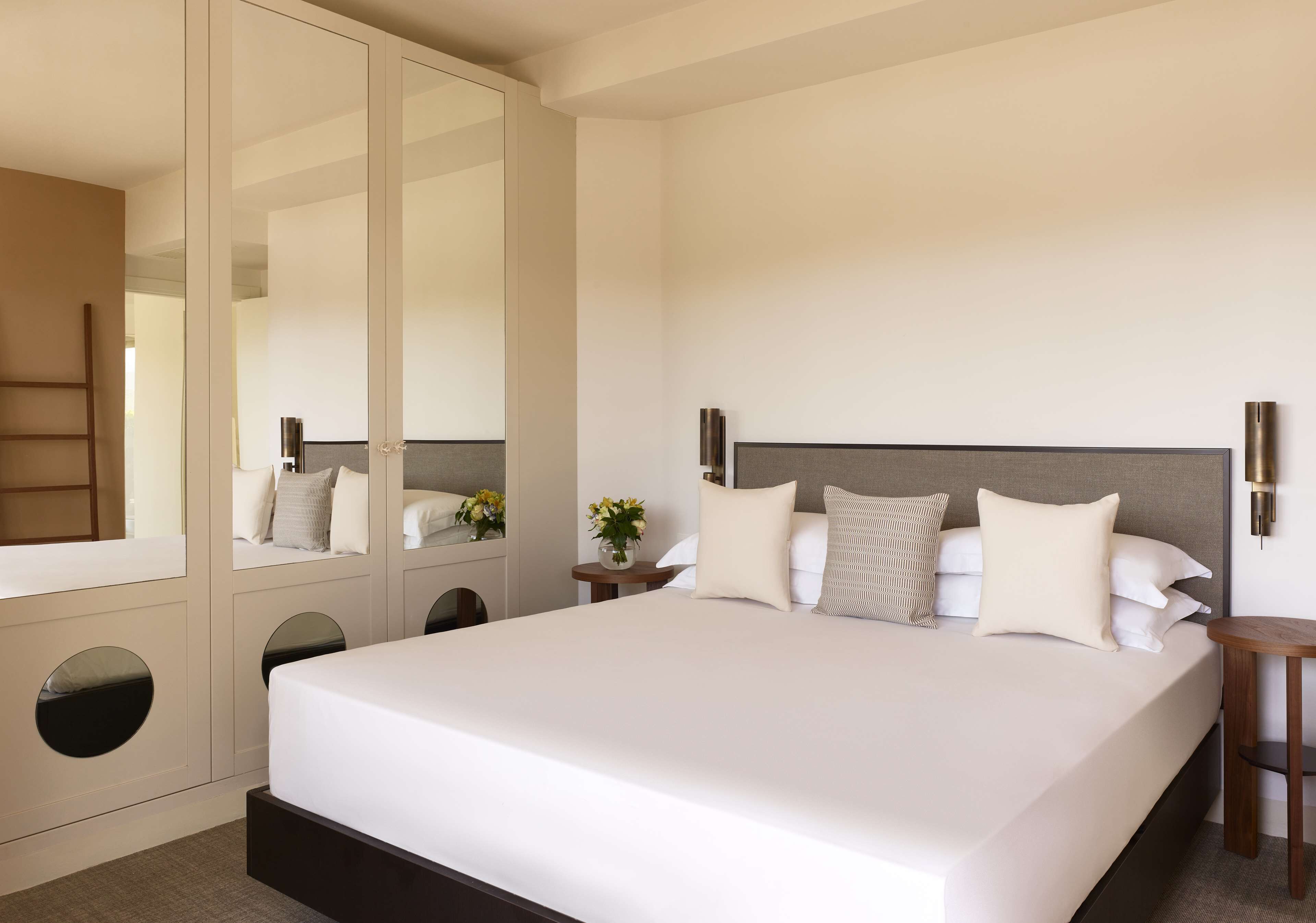 Una cama grande con cabecera de madera, un espejo y dos mesitas de noche con lámparas.