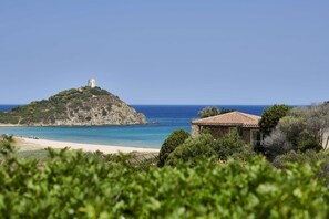 Un paisaje costero con una colina que presenta una torre, una playa y un edificio con techo de tejas.