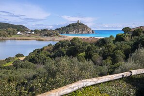 Un paisaje costero con una colina que presenta una torre, una playa y una masa de agua.
