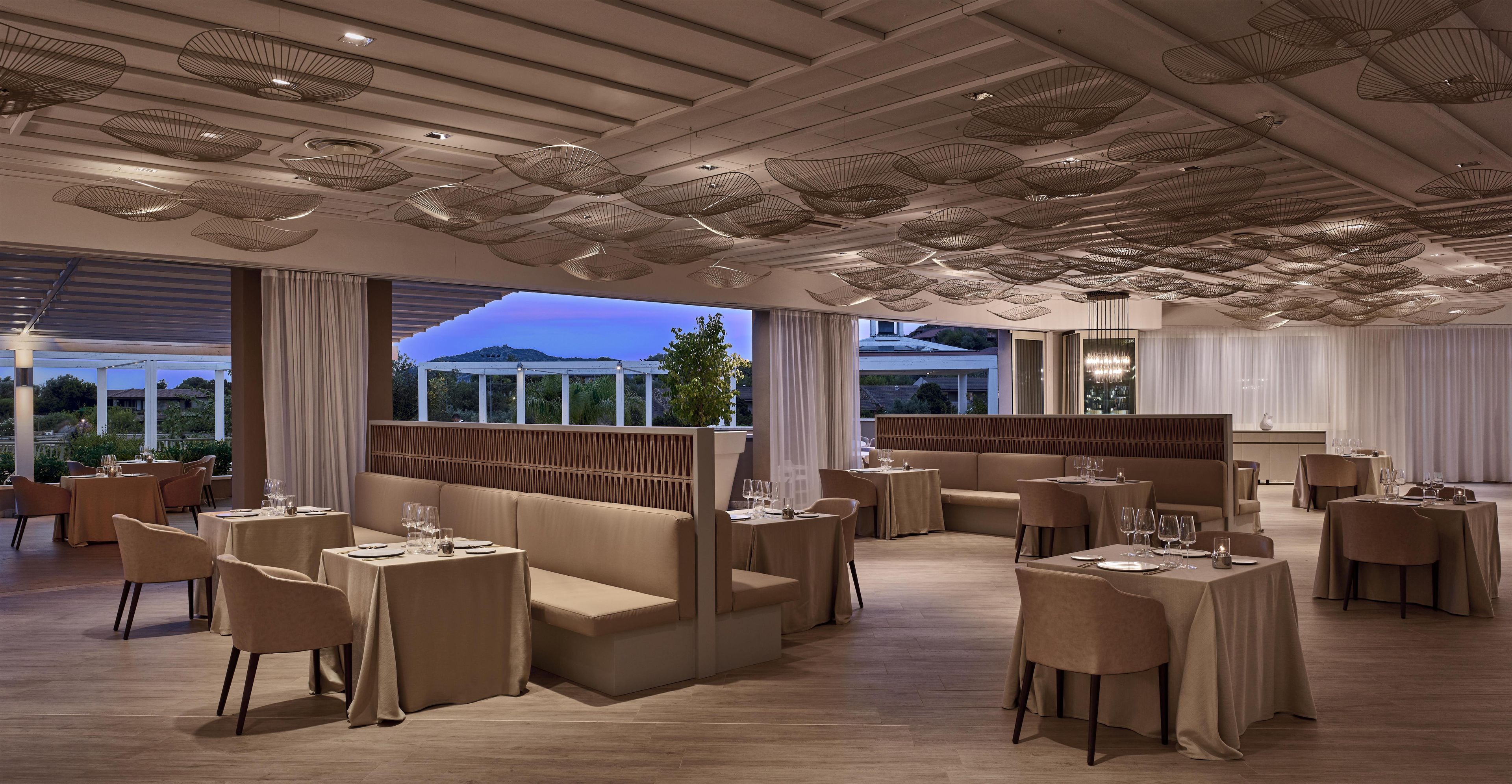 Ein Restaurant mit modernem Ambiente, das eine Mischung aus Sitzgelegenheiten wie Boxen und Tische bietet und einen Blick ins Freie gewährt.