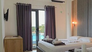 A hotel room with two beds, a wooden cabinet, a view of the pool, and an air conditioning unit. - Esmerald Hotel (Ksamil)
