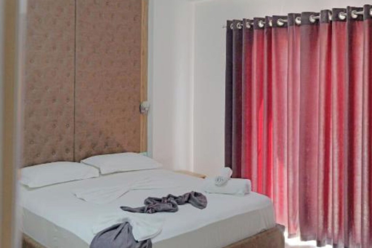 A bedroom with a bed, a wardrobe, and a curtain.