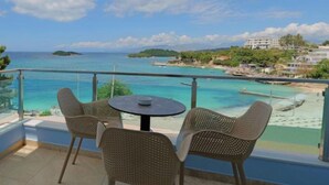 A balcony with a table and chairs overlooking a beach and ocean. - Esmerald Hotel (Ksamil)